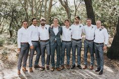 a group of men standing next to each other in front of trees and dirt ground