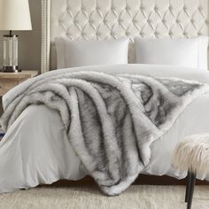 a bed with white linens and a fur blanket