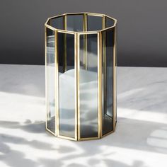 a glass vase sitting on top of a white table next to a shadow cast wall