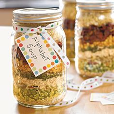 three jars filled with food sitting on top of a table next to labels and ribbons