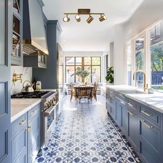 a kitchen with blue cabinets and tile flooring, along with a dining table in the center