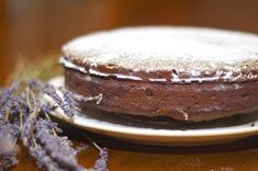 a chocolate cake sitting on top of a white plate next to lavender sprigs