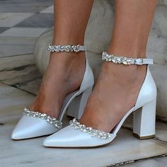 a woman wearing white high heel shoes with crystal embellishments