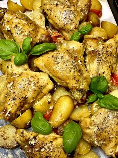 chicken, potatoes and basil on a plate ready to be cooked in the oven for dinner