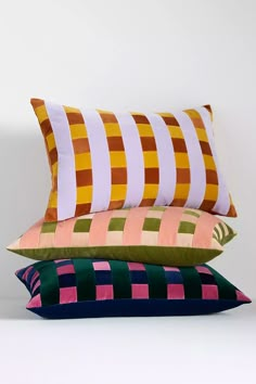 four pillows stacked on top of each other in different colors and patterns, one is multicolored