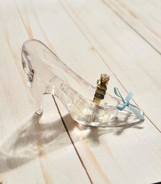 a clear glass shoe with a blue ribbon on the side and a tiny gold crown on top