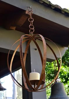 a wooden chandelier hanging from the side of a building with two bells in front of it