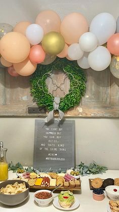 a table filled with food and balloons in the shape of a wreath on top of it