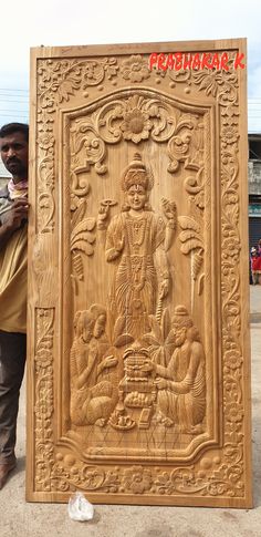 a man standing next to a carved wooden plaque