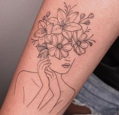 a woman's arm with flowers on it and her face in the center,