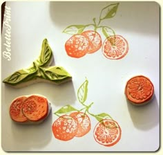 some oranges are cut into pieces and placed on top of a white surface with green leaves