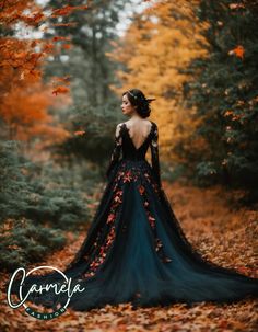 a woman in a black and blue dress is standing in the woods surrounded by leaves