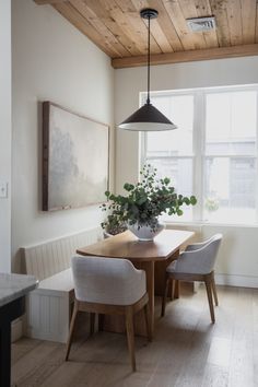 a dining room table with two chairs and a potted plant on top of it