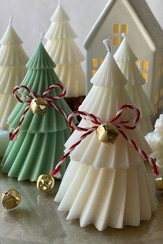 small christmas trees with bells on them are sitting in front of other ornaments and decorations