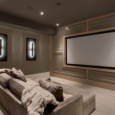 a large couch in front of a projector screen with two pillows on the back