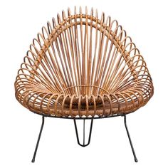 a wicker chair with metal legs and an iron frame on the bottom, sitting in front of a white background