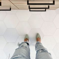 the legs of a person standing in front of a tile floor with hexagonal tiles