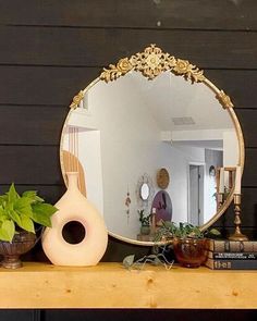 a mirror sitting on top of a mantle next to a potted plant