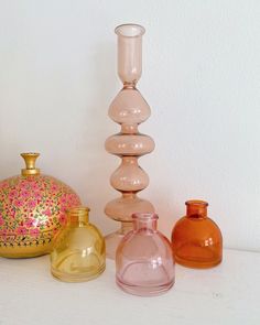 several vases are lined up next to each other on a table with a white wall in the background