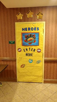 there is a yellow door with stickers on it in the hallway that says, heros enter here