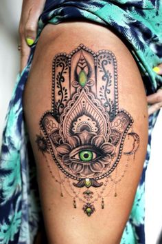 a woman's thigh with an ornate hamsa tattoo on her leg and eye in the middle