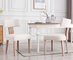 two white chairs sitting at a table in a room