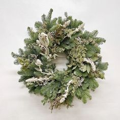 a green wreath with white flowers and greenery