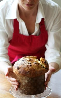 a woman holding a muffin on top of a glass plate