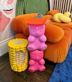 there is a pink teddy bear sitting on the floor next to some other toys and decor