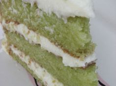 a piece of green cake with white frosting and sprinkles on top