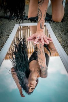 a woman is upside down in the water with tattoos on her arm and leg,