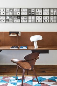 a desk with a chair, lamp and pictures on the wall in front of it