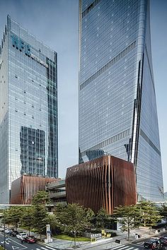 two very tall buildings next to each other on a city street with cars driving by