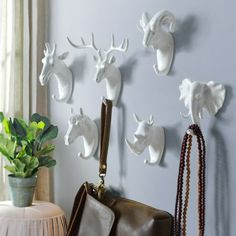 there are many white deer heads on the wall and purses hanging from it's hooks