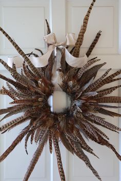 a wreath made out of feathers hanging on a door with a ribbon tied around it