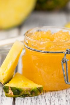 a pineapple jam in a glass jar next to a sliced pineapple