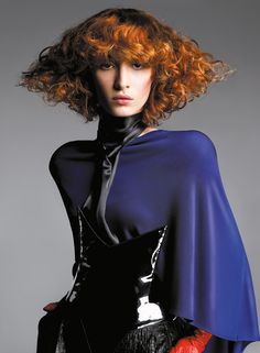 a woman with red hair wearing a blue cape