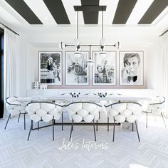 an elegant dining room with white chairs and black and white wall art above the table