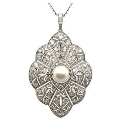 The pendant, an Art Deco masterpiece, is designed from fine platinum, intricately woven like a delicate, precious web. Adorned with 89 brilliant-cut diamonds, H-I in color and vs-si in clarity, totaling 2.80 carats, it glistens like dewdrops in the morning. At its heart rests a single natural pearl, adding a touch of timeless elegance. Unveiling its secret, the pendant can transform into an elegant brooch, adapting seamlessly to any occasion with grace and versatility. Platinum 950 89 diamonds, Luxury Art Deco Pendant Necklace, Art Deco Necklace Pendant, Art Deco Jewelry 1920s, Art Deco Pearl, 1920s Necklace, Art Deco Pendant Necklace, Elegant Brooch, Art Deco Pendant, Art Deco Necklace