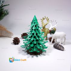 a small christmas tree next to some fake animals and pine cones on a white surface