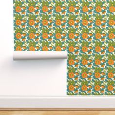 an orange and green flower pattern on a wall next to a roll of toilet paper