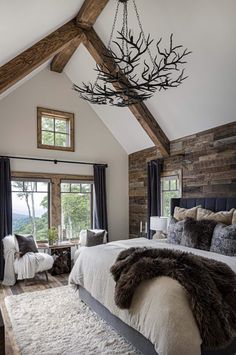 a large bed sitting in a bedroom under a chandelier above a wooden ceiling