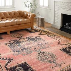 a living room filled with furniture and a rug on top of a hard wood floor