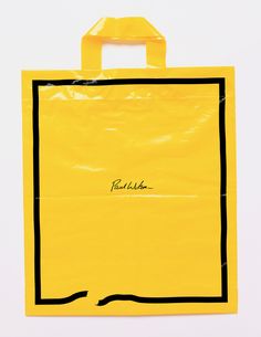 a yellow shopping bag with black writing on the front and bottom, sitting against a white background