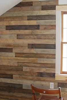 a chair sitting in front of a wall made out of wood planks with an open window