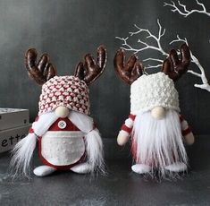 two knitted christmas gnomes with antlers on their heads, one wearing a red and white hat