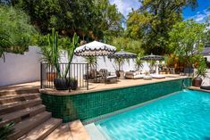 an outdoor swimming pool with steps leading up to it and umbrellas on the deck