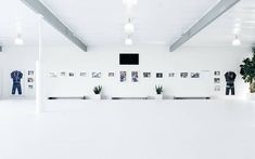 an empty room with pictures on the wall and potted plants in front of it