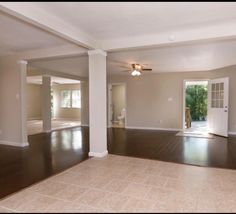 an empty living room with hard wood floors and white columns on either side of the door