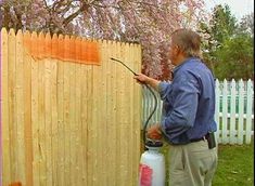 a man is painting the fence with an airless paint sprayer in his backyard